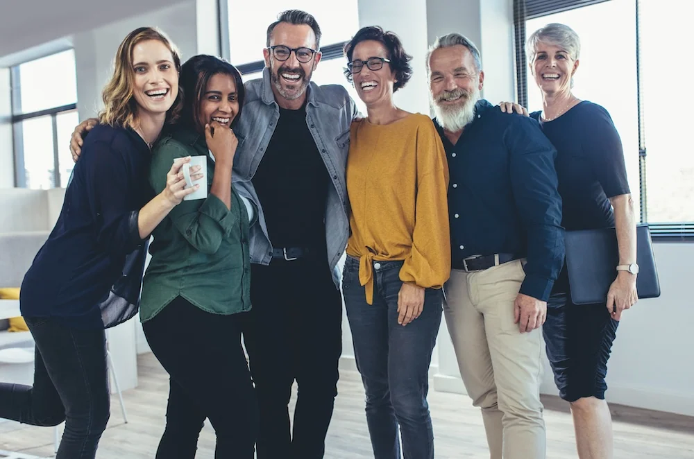 Une équipe de six professionnels souriants dans un bureau lumineux — photo d’illustration Adobe Stock.