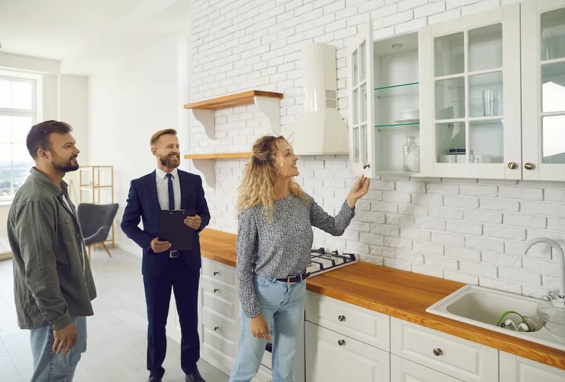 Un professionnel accompagne deux personnes lors d’une visite immobilière — photo d’illustration.